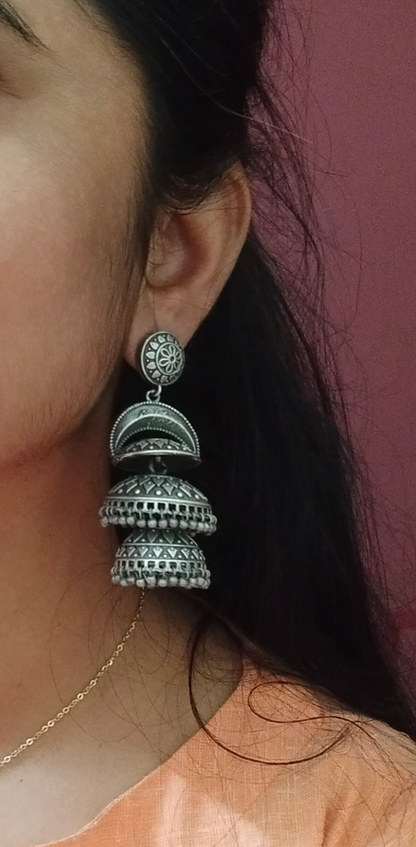 Close-up of a person wearing a silver and black earrings with a blurred background, silver earring, Jhumka